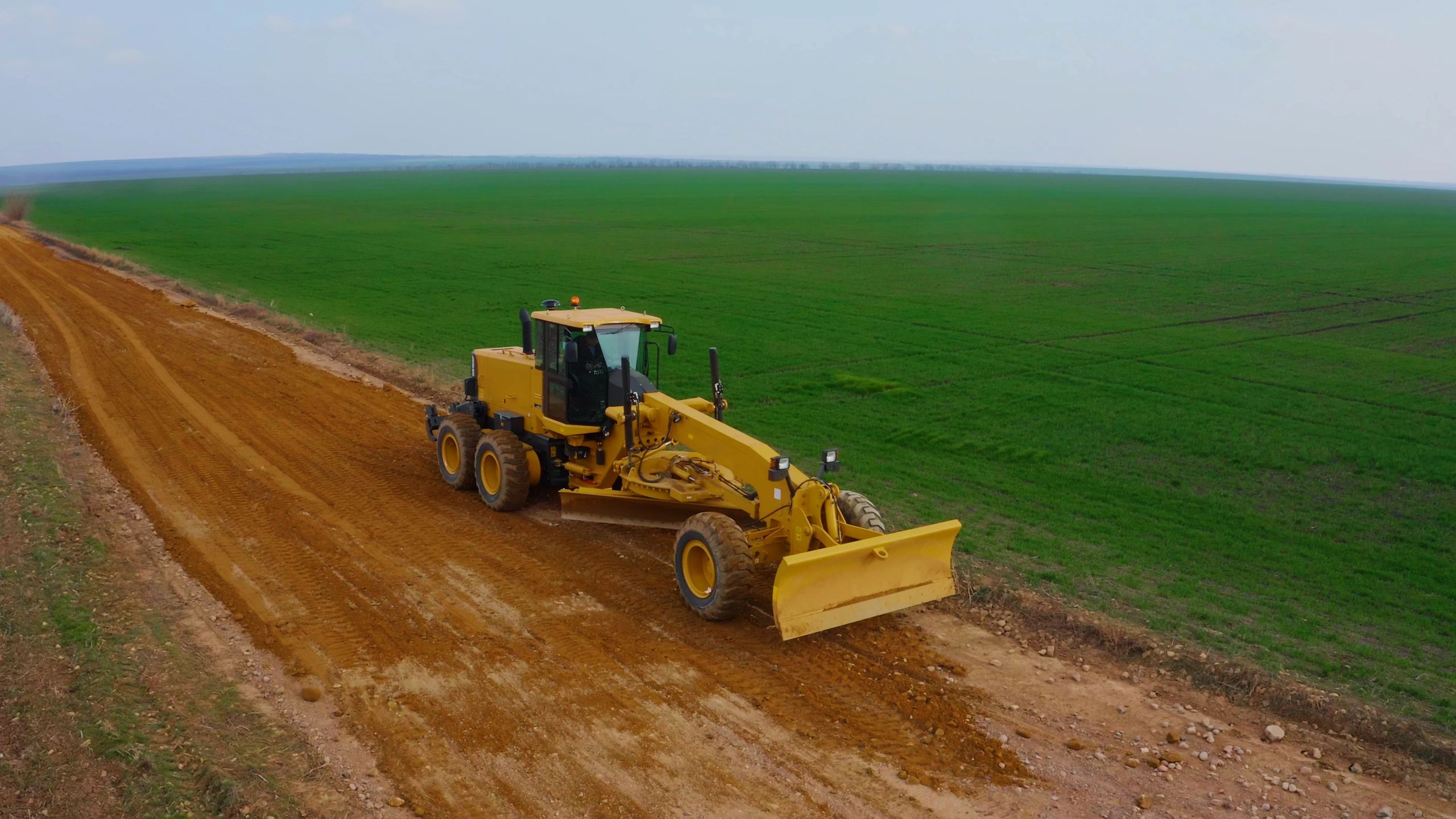 Grader shaping and leveling a dirt road